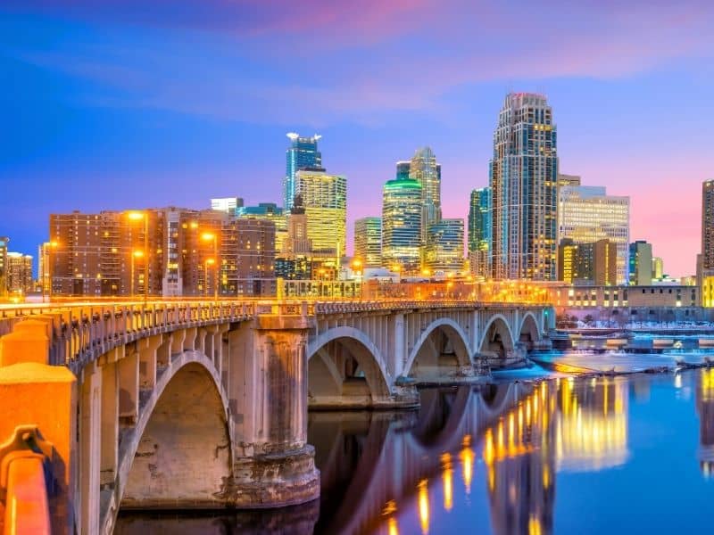 Minneapolis skyline with illuminated bridge, river reflections, and downtown cityscape for Minneapolis land surveying services